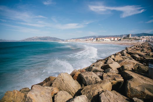 Breathtaking seaside view with a rocky shoreline and vibrant cityscape in the distance.