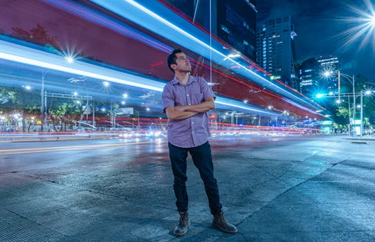 Man stands confidently with light trails from passing traffic in Mexico City's vibrant nightlife.