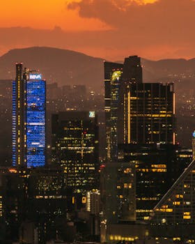 Stunning sunset view of Mexico City's modern skyline with illuminated skyscrapers.