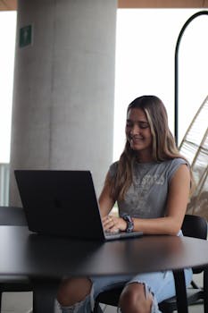 Young woman using a laptop in a modern indoor setting, focused on online study.